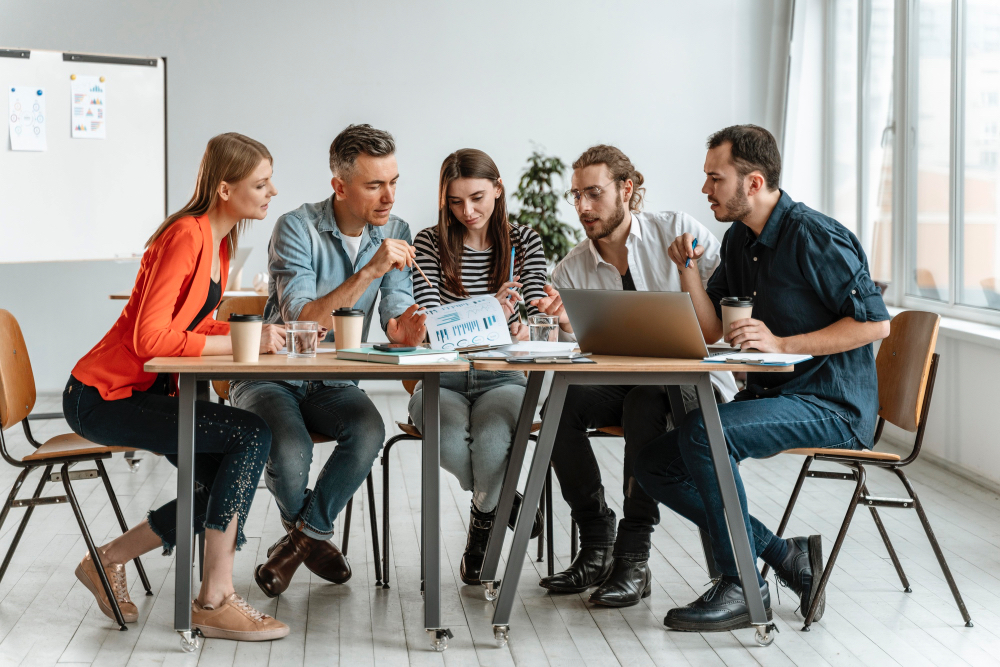Team sitting on chairs next to a table talking